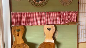 Ein Zimmer mit zwei Holzsesseln, einer grünen Wand und drei dekorativen Spiegeln.