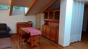 Ein gemütliches Zimmer mit einem Holzesstisch, einer Couch und einer Küchenzeile mit Holzschränken und einem Fenster.