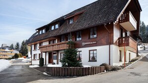 A two-story building with a balcony, a small Christmas tree, and a sign that reads 'Feriwerhaus Haus Schwab.' - Apartment 'Weideglück' with Shared Garden, Balcony and Wi-Fi (Feldberg-Altglashütten)