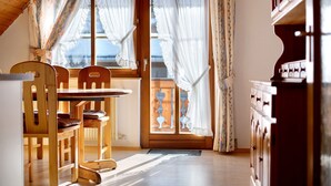 A dining area with wooden chairs and a table, a wooden cabinet, and a window with curtains. - Apartment 'Weideglück' with Shared Garden, Balcony and Wi-Fi (Feldberg-Altglashütten)