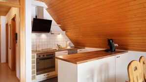 A kitchen with a wooden ceiling, white cabinets, a built-in oven, and a black coffee maker on the counter. - Apartment 'Weideglück' with Shared Garden, Balcony and Wi-Fi (Feldberg-Altglashütten)