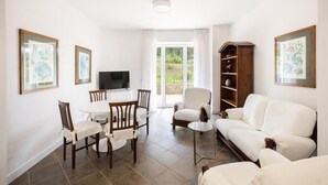A living room with a white sofa, a dining table with chairs, a TV, and a bookshelf. - Glicine- 03 bedroom apartment with private terrace (Massa Lubrense)