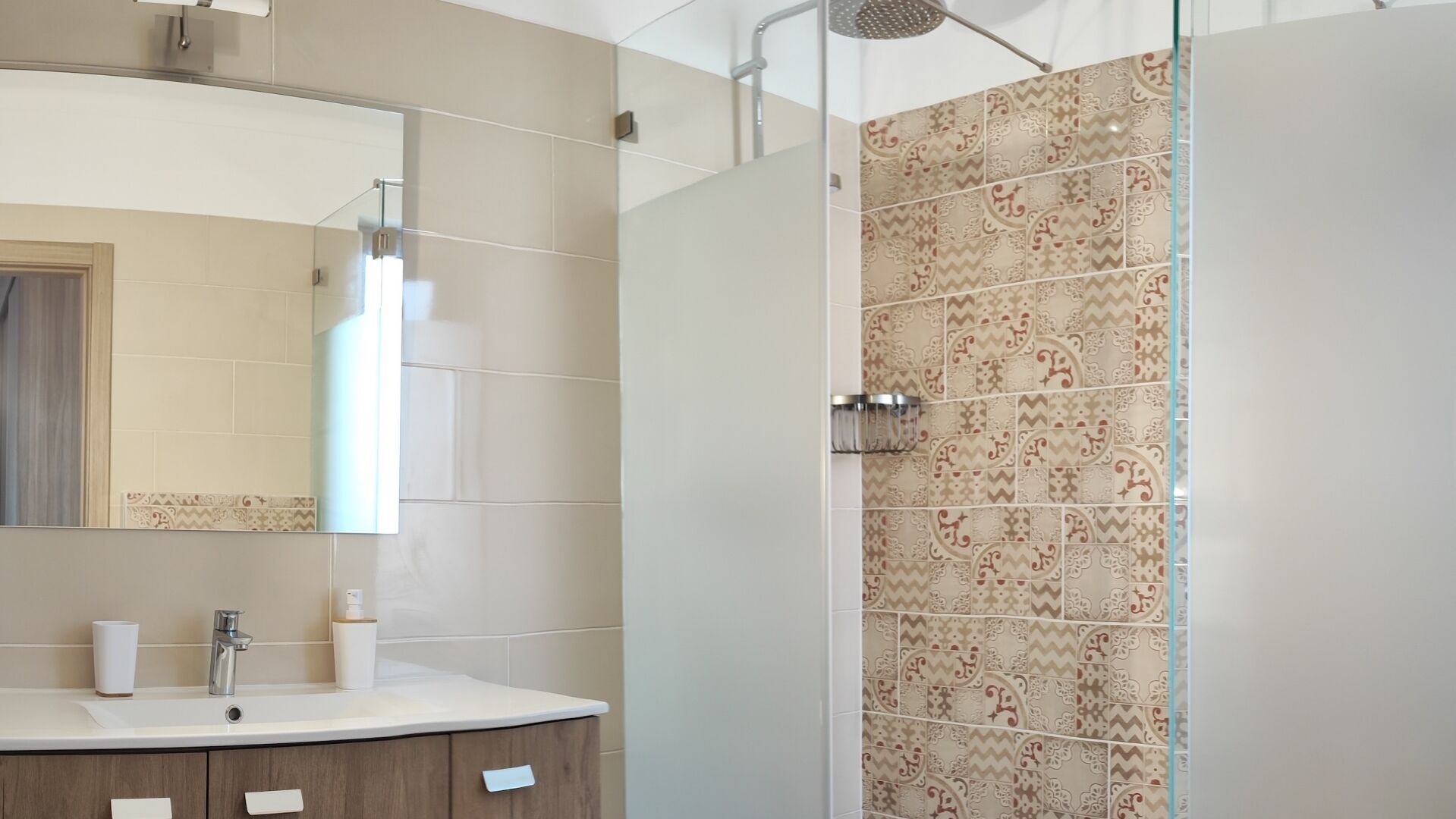 Een moderne badkamer met een grote spiegel, een wastafel en een douche met patroontegels.