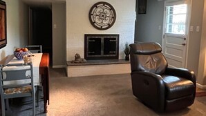 A living room with a fireplace, a dining area with a table and chairs, and a leather recliner.