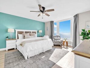 A bedroom with a bed, nightstands, a chair, a window with a view, and a ceiling fan. - 🏝️BEACH FRONT | Gulf Views | Great Amenities | Emerald Beach 1831🏝️ (Panama City Beach)