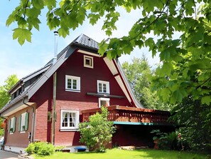 Ein rotes Haus mit einem geneigten Dach, weißen Fenstern und einer kleinen Veranda.