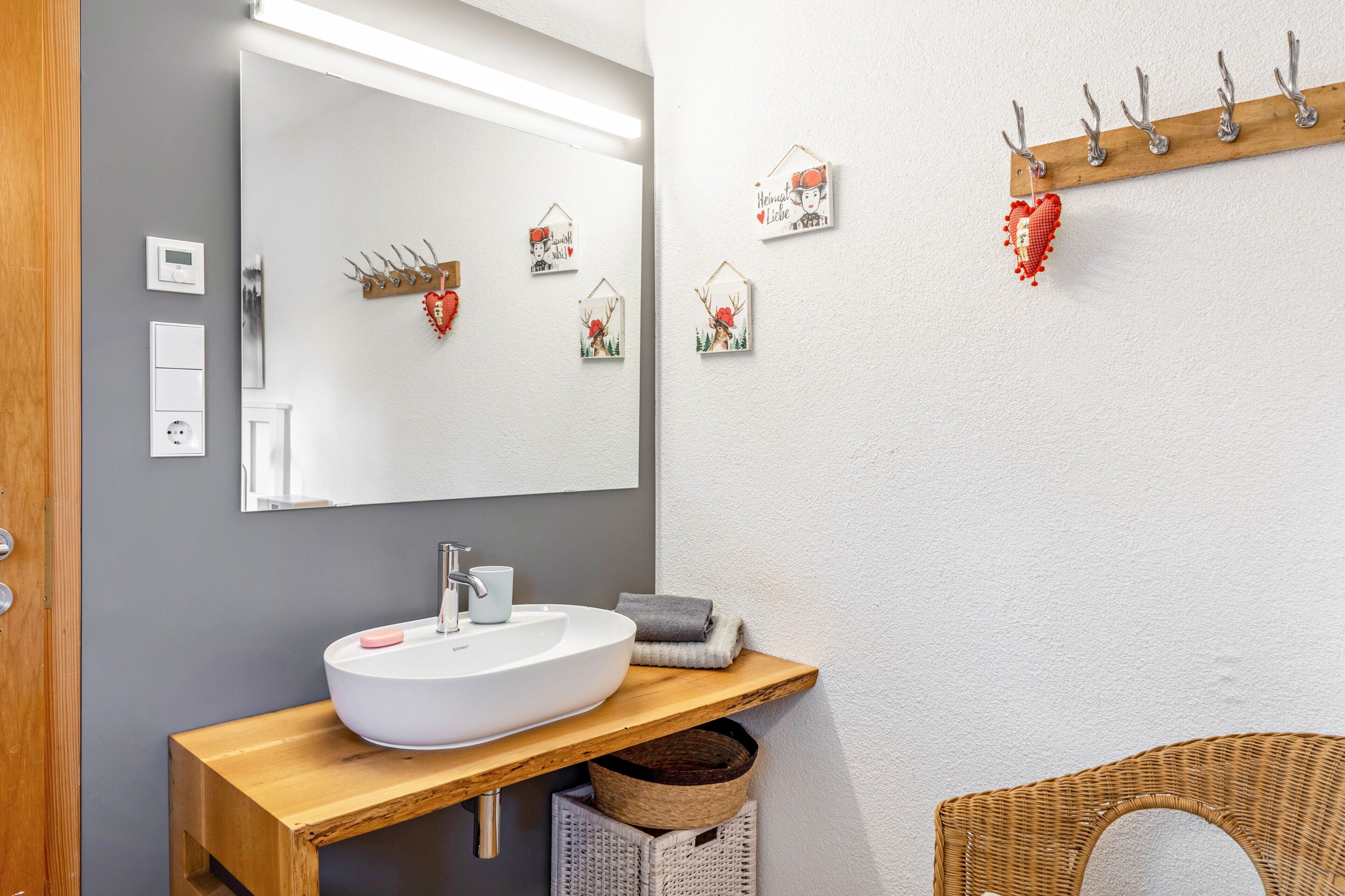 A bathroom with a wooden vanity, a white sink, a mirror, and a wall-mounted towel rack.
