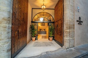 A hotel entrance with a wooden door, a tiled floor, and a reception area visible through an arched window. - Hotel San Lorenzo Catedral (València)