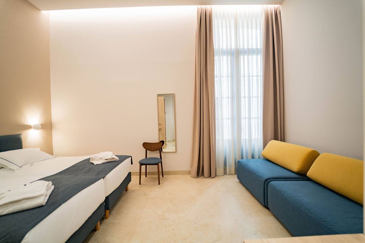 Une chambre d’hôtel avec un lit, une chaise, un canapé et un miroir.