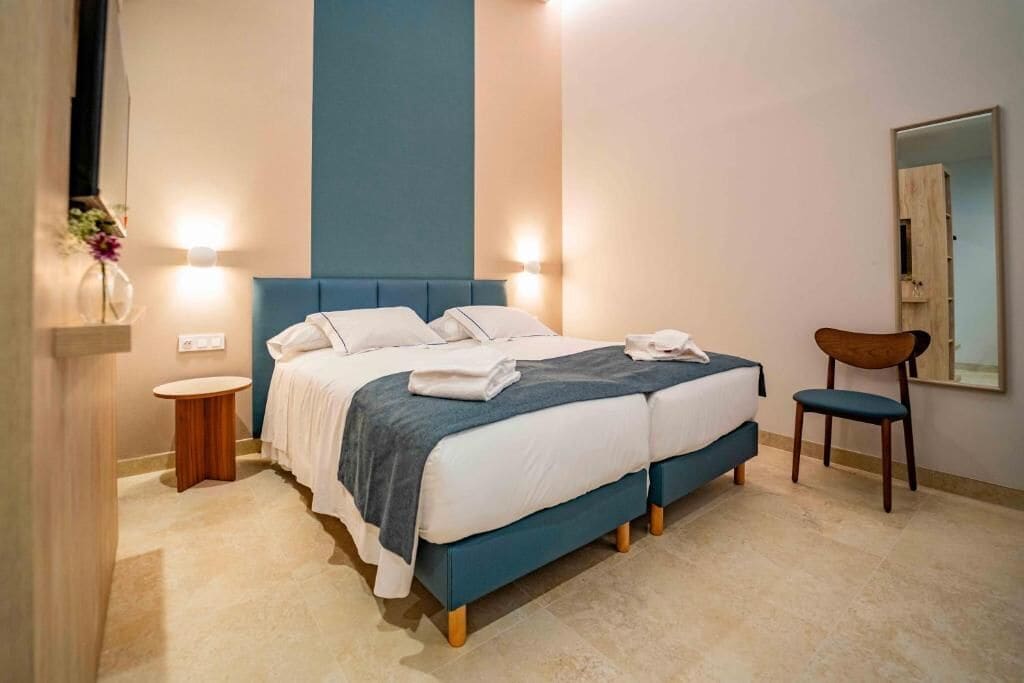A bedroom with a bed, bedside tables, a chair, and a mirror.