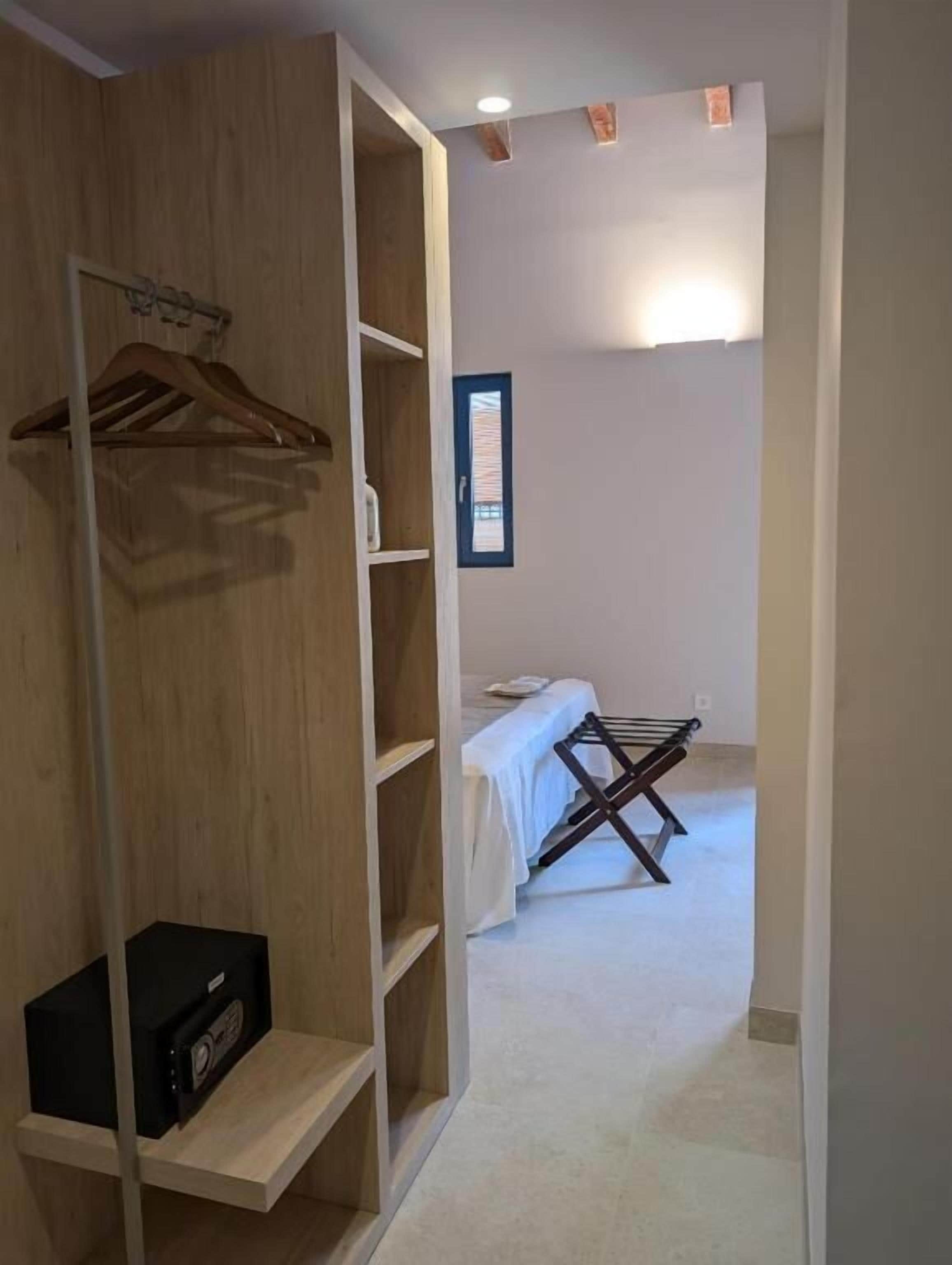 Ein Zimmer mit Holzschrank, Bett mit weißer Bettdecke und Wäscheständer.