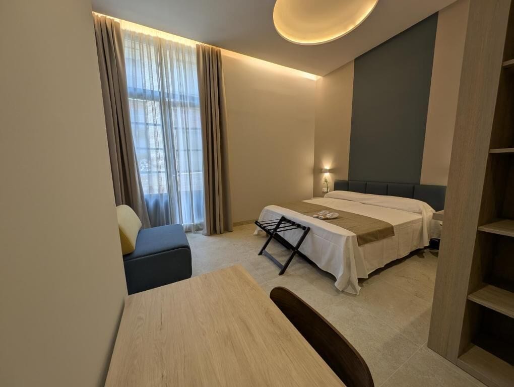A modern hotel room with a bed, a desk, and a chair.