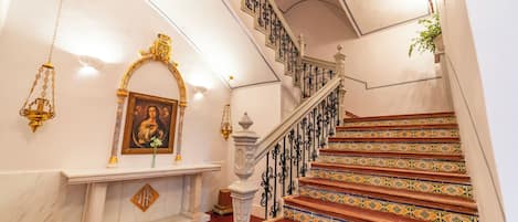 Una imponente escalera con barandillas decoradas y peldaños estampados, que conduce a un piso superior.