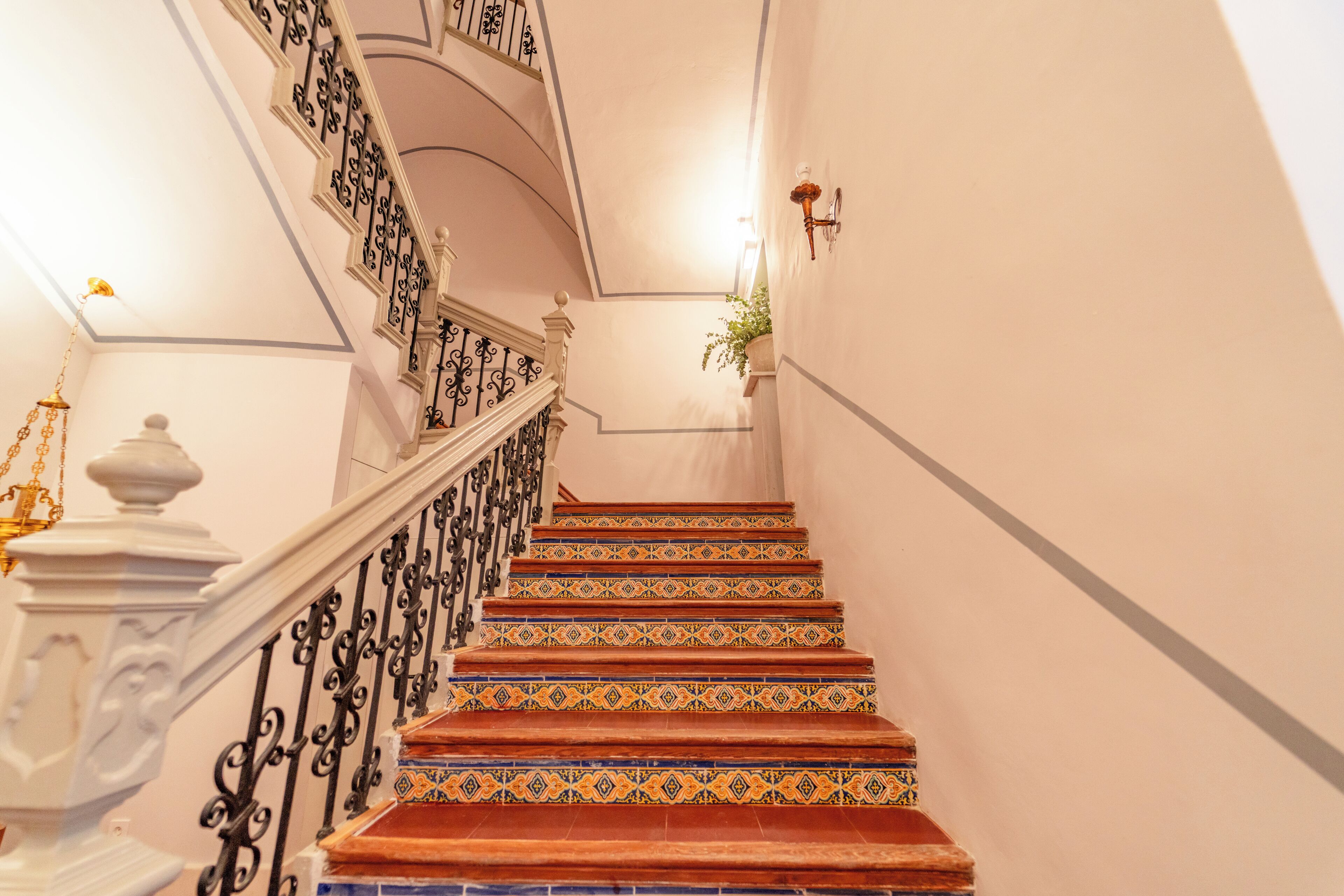 A staircase with ornate black railings and patterned red, blue, and yellow tiles.