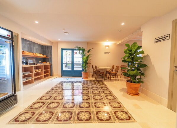 A hotel lobby with a reception desk, a seating area with chairs, a large potted plant, and a tiled floor. - Hotel San Lorenzo Catedral (València)