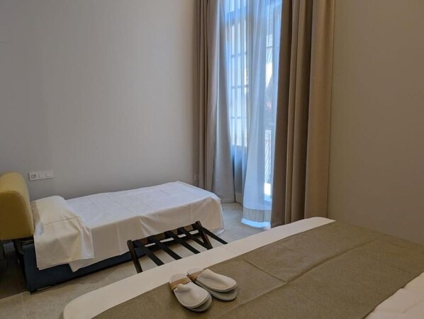 A small, clean room with a bed, a chair, and a window with curtains. - Hotel San Lorenzo Catedral (València)