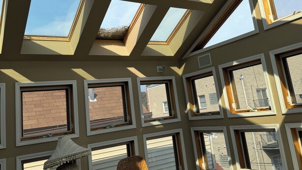 Une pièce dotée de lucarnes, d’un ventilateur de plafond, de chaises en osier et d’une table.