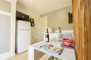 A kitchen with a refrigerator, microwave, and a dining area with a plate, wine bottle, and basket.