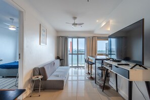 Eine moderne Wohnung mit Sofa, Essbereich, Fernseher und Blick auf die Stadt.