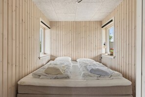 A narrow room with a bed, wooden walls, and a window. - Renovated beach house with unique location (Bjert)