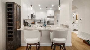 A modern kitchen with a central island, white cabinetry, and pendant lighting.