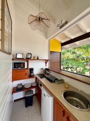 Una cocina compacta con microondas, tostadora, cafetera y un refrigerador pequeño.