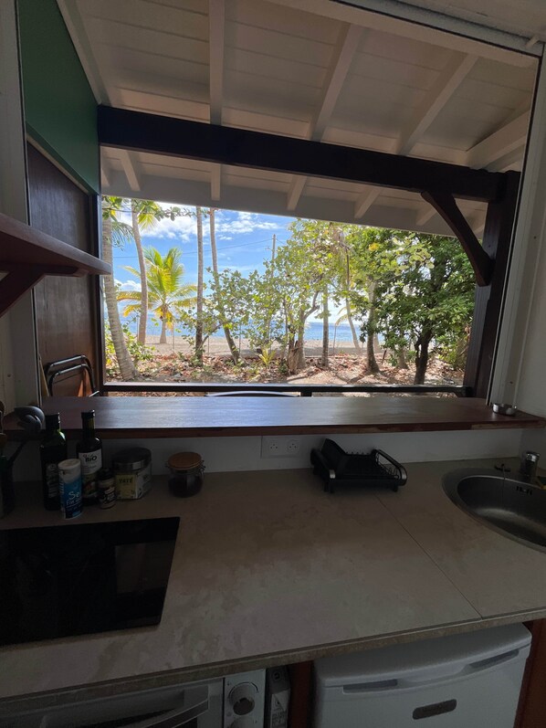 Una cocina con vista a la playa, un lavamanos y diversos utensilios de cocina.