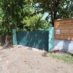 A gated area with a green metal gate, a concrete wall, and a wooden fence.
