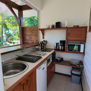 Una cocina compacta con un lavamanos, un microondas, una cafetera y un pequeño bote de basura.