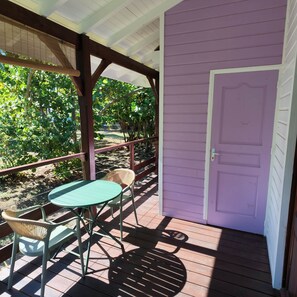 Une véranda abritée avec une table et des chaises, une porte et une vue sur un jardin.
