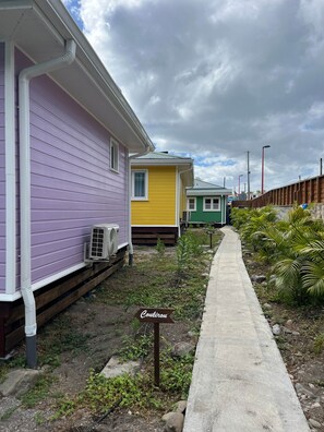 Une rangée de maisons mobiles aux couleurs vives, avec un chemin en béton et une pancarte indiquant « Coulirou ».
