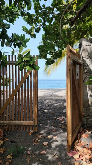 A wooden gate leading to a beach with a clear view of the ocean. - Beach Bungalow: Thazard (Le Carbet)