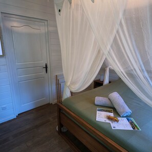 Ein Zimmer mit einem Bett, einer Tür und einem Nachttisch mit Handtuch und Broschüre.