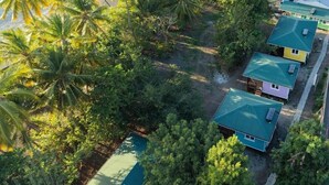 An aerial view of a coastal area with a row of houses, a dock, and a clear view of the sea with boats. - Beach bungalow: Balaou (Le Carbet)