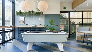 A pool table in a modern lounge area with bar stools, a counter, and a staircase leading to an upper level. - For Students Only Studios in Plymouth (Plymouth)