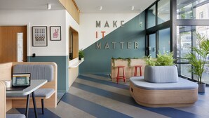 A modern lounge area with seating, a laptop on a table, and a motivational wall with the text "MAKE IT MATTER". - For Students Only Studios in Plymouth (Plymouth)