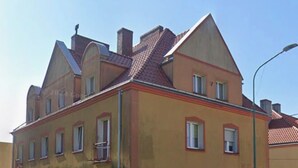 Un edificio de varios pisos con fachada amarilla, múltiples ventanas y techo inclinado.
