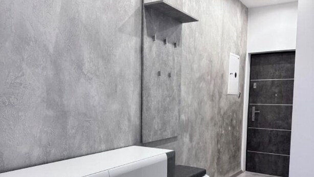 Una cocina moderna con encimera gris, armarios blancos y salpicadero negro.