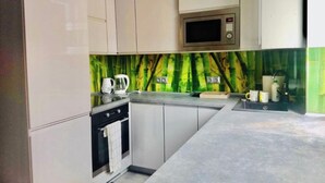 Una cocina moderna con armarios blancos, un microondas y un salpicadero con diseño de bambú verde.