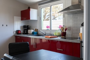 Una cocina con armarios rojos, una ventana y un lavamanos.
