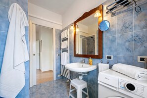 A bathroom with a sink, mirror, towel rack, and a washing machine. - Apartment 'Il Boma - Capitan Libeccio' with Lake View, Wi-Fi and Air Conditioning (Garda)