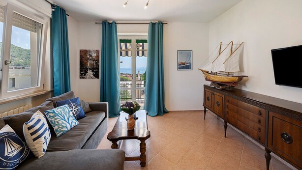 Un salon comprenant un canapé, une table basse, un téléviseur, un meuble et une vue sur l’extérieur, visible à travers une porte.