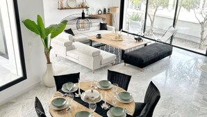 A modern living room with a dining area, featuring a large window, a potted plant, and a sofa set. - La Casa Verde , Duplex in the Heart of La Marsa (La Marsa)