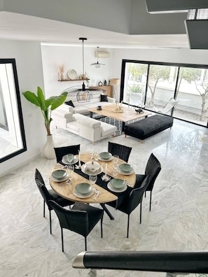 A modern living room with a dining area, featuring a large window, a potted plant, and a sofa set. - La Casa Verde , Duplex in the Heart of La Marsa (La Marsa)