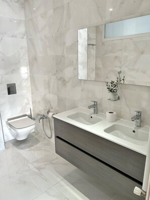 Ein modernes Badezimmer mit einem Doppelwaschtisch, einer Toilette und einem Bidet.