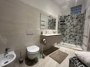 Un baño moderno con inodoro, lavamanos y ducha.