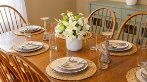 A dining table set with plates, cutlery, and glasses, surrounded by wooden chairs. - Ann Inn - Downtown New Milford Apartment (New Milford)