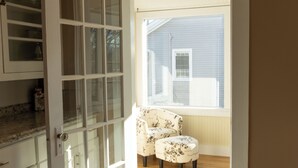 An open door leading to a room with a wooden floor, a window, and a chair. - Ann Inn - Downtown New Milford Apartment (New Milford)