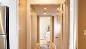 A hallway with wooden flooring, white walls, and a door leading to another room. - Ann Inn - Downtown New Milford Apartment (New Milford)