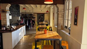 A cozy restaurant with a wooden table and yellow chairs, a bar area with bottles, and a chalkboard menu. - Motel - Usine à Gaz (Bourgueil)
